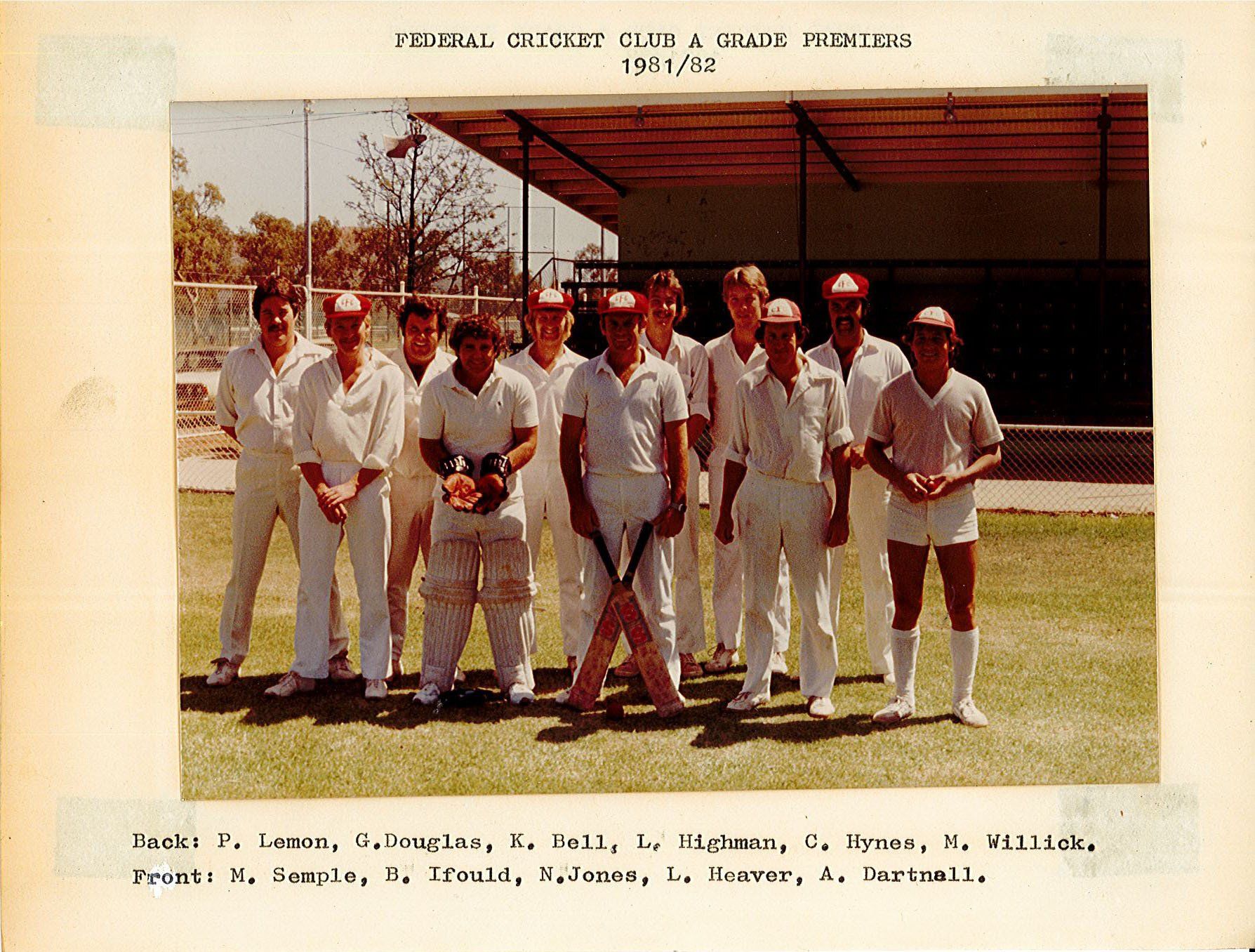 A group of men are posing for a picture with a cricket bat in the middle