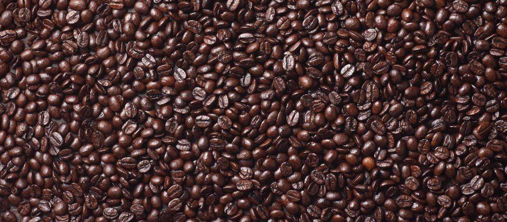 Close-up view of roasted coffee beans. Dark brown beans densely packed.