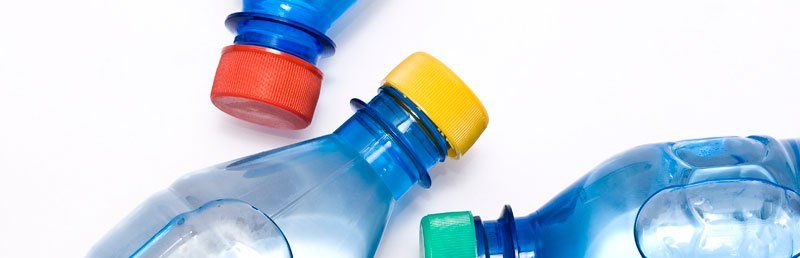 Several clear plastic water bottles with colorful caps on a white background.