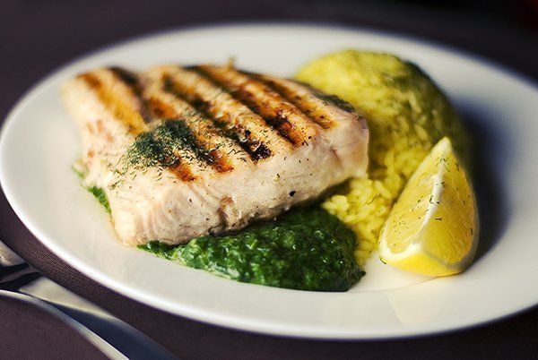 A white plate topped with grilled fish and mashed potatoes