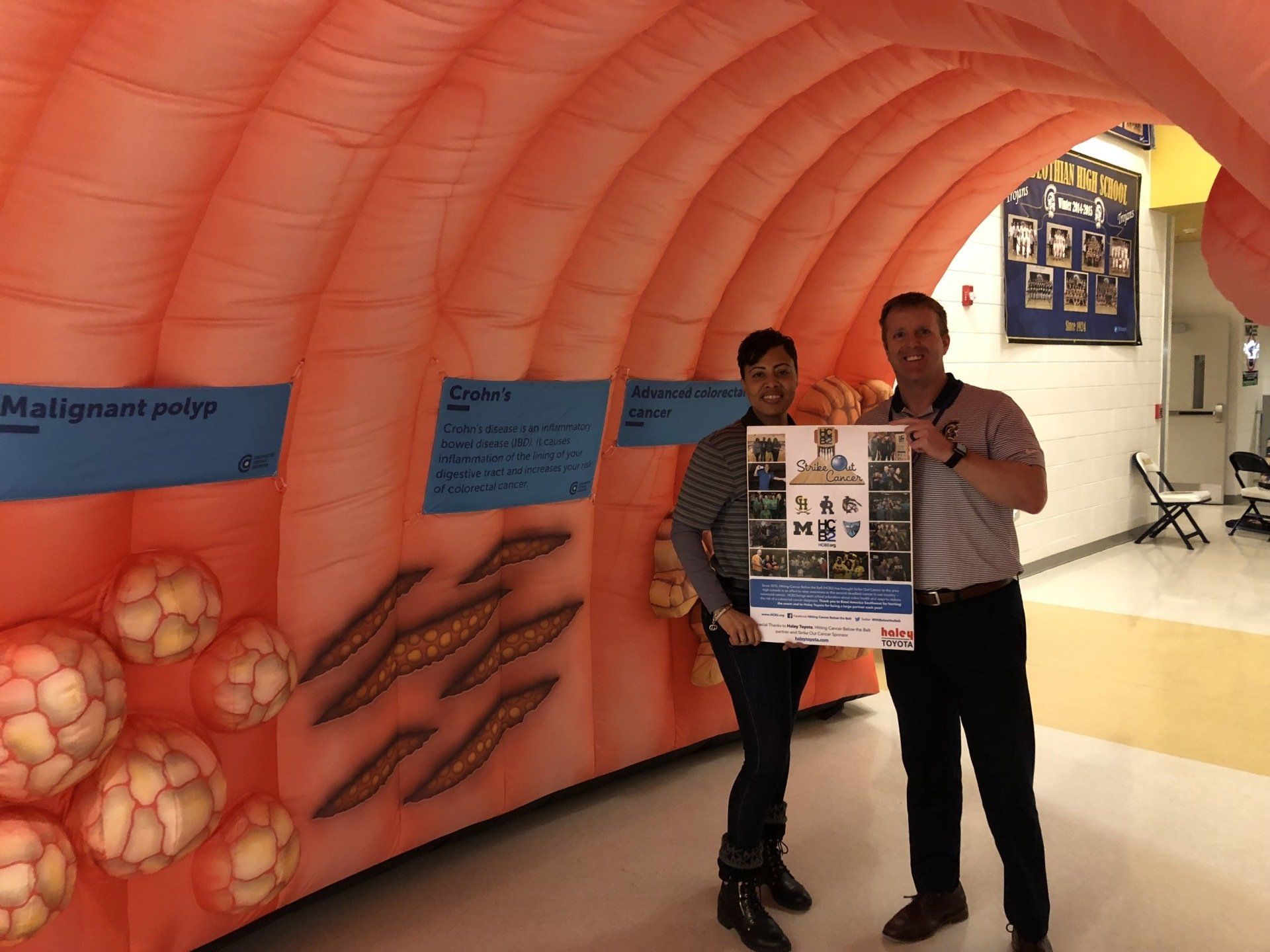 A man and a woman are standing in front of an inflatable model of a large intestine.
