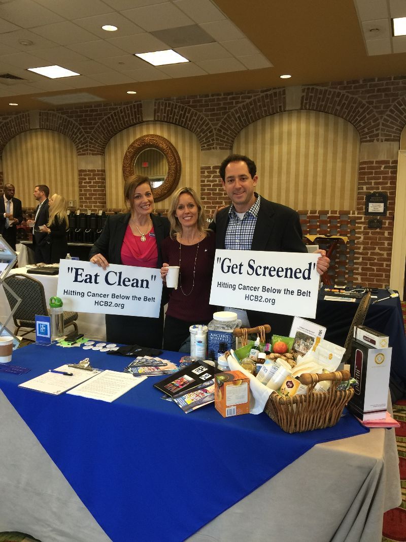 A group of people standing around a table holding signs that say get screened