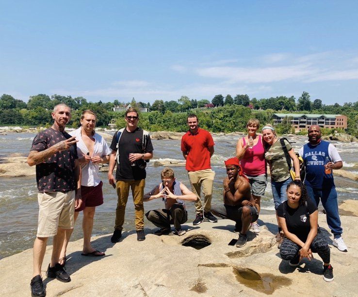A group of people are posing for a picture in front of a body of water.