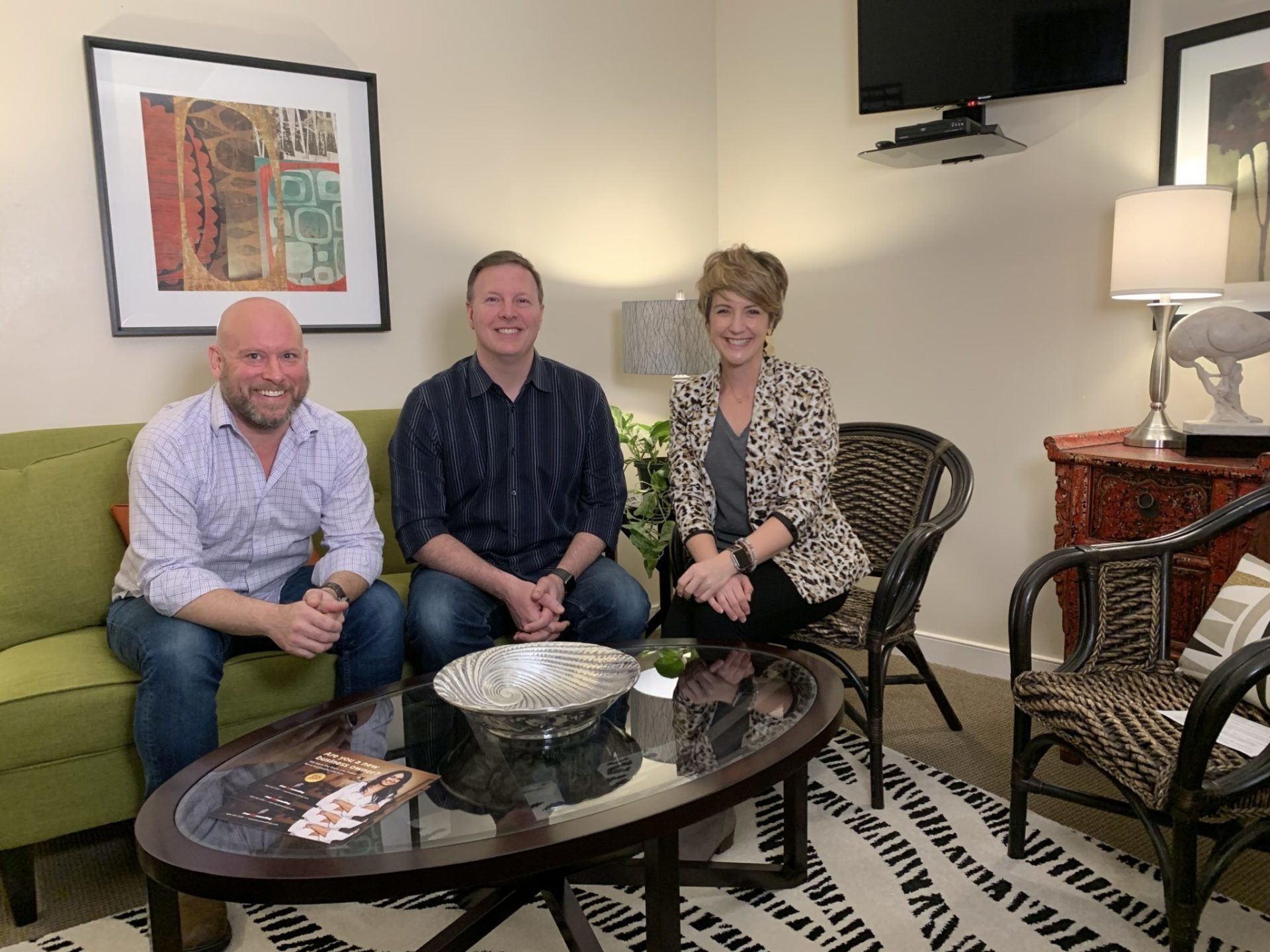 Three people are sitting on a couch in a living room.