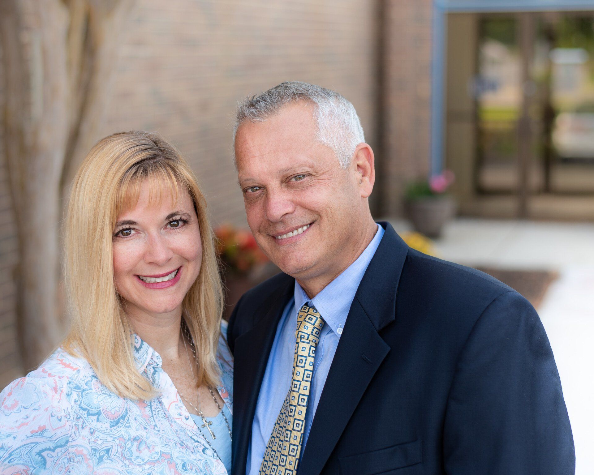 A man and a woman are posing for a picture in front of a building.
