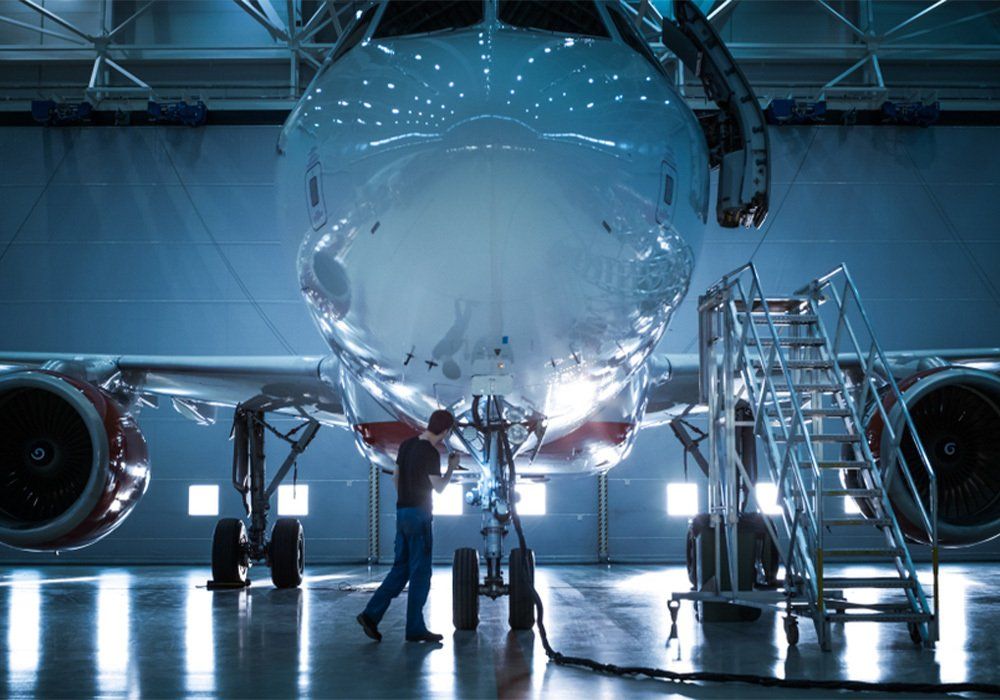 Brand New Airplane Standing in a Aircraft Maintenance Hangar while Aircraft Maintenance Engineer-Technician-Mechanic goes inside Cabin via Ladder-Ramp