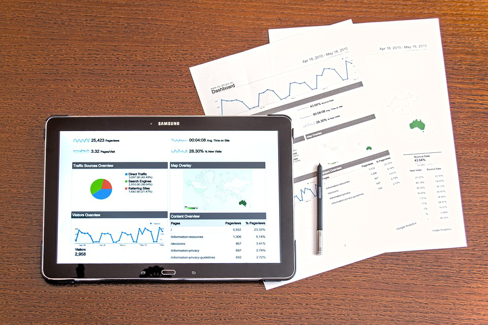 a tablet is on a table next to papers and a pen