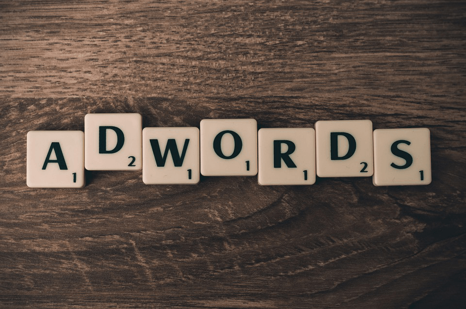 scrabble tiles spell out the word adwords on a wooden table