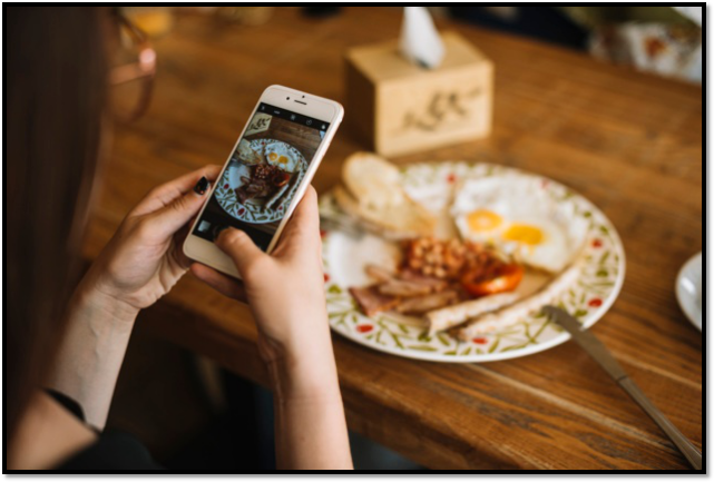 a woman is taking a picture of a plate of food on her phone