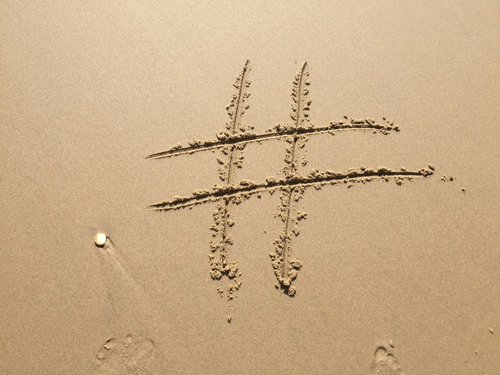 a hashtag is drawn in the sand on a beach