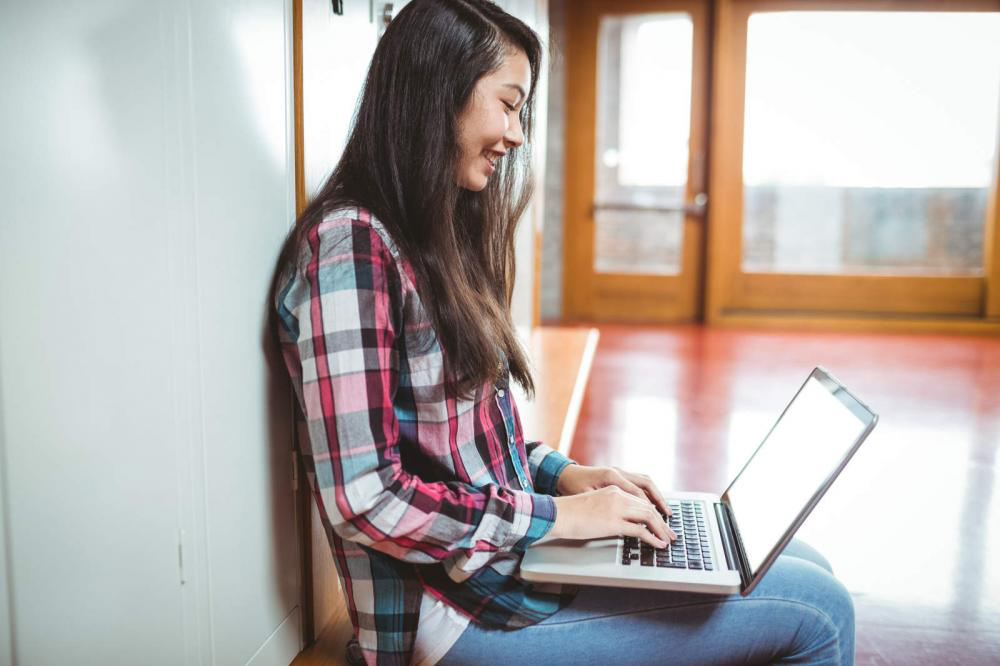 a woman is sitting on the floor using a laptop computer .