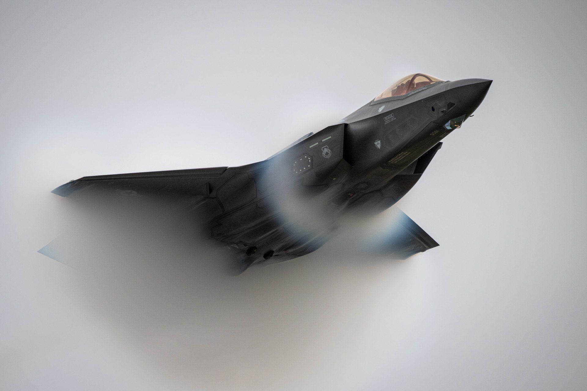 A fighter jet is flying through a cloudy sky.