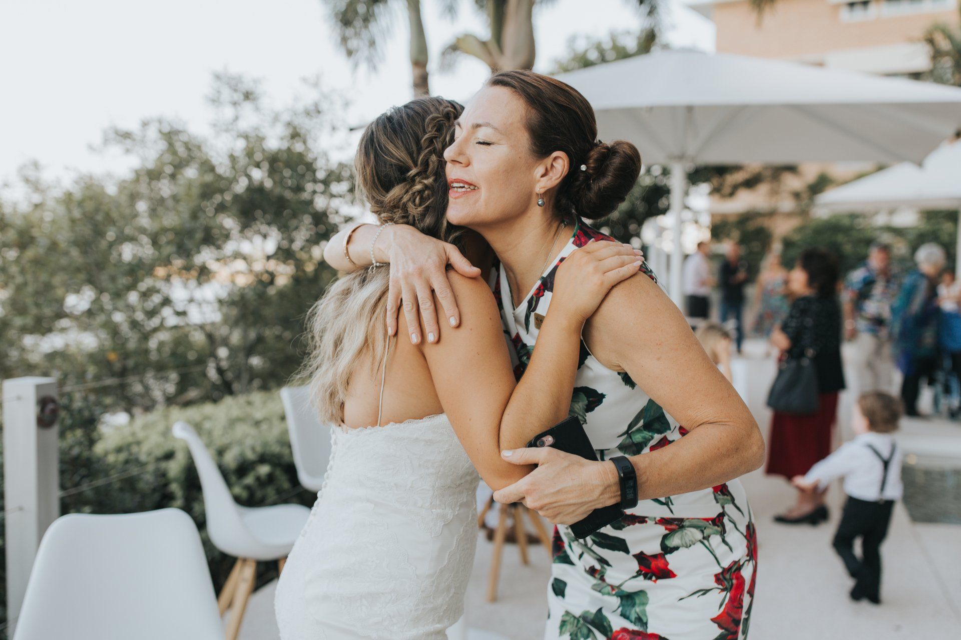 bride hugging celebrant after their wedding at Maroochydore restaurant, wearing white, celebrant in white and red dress