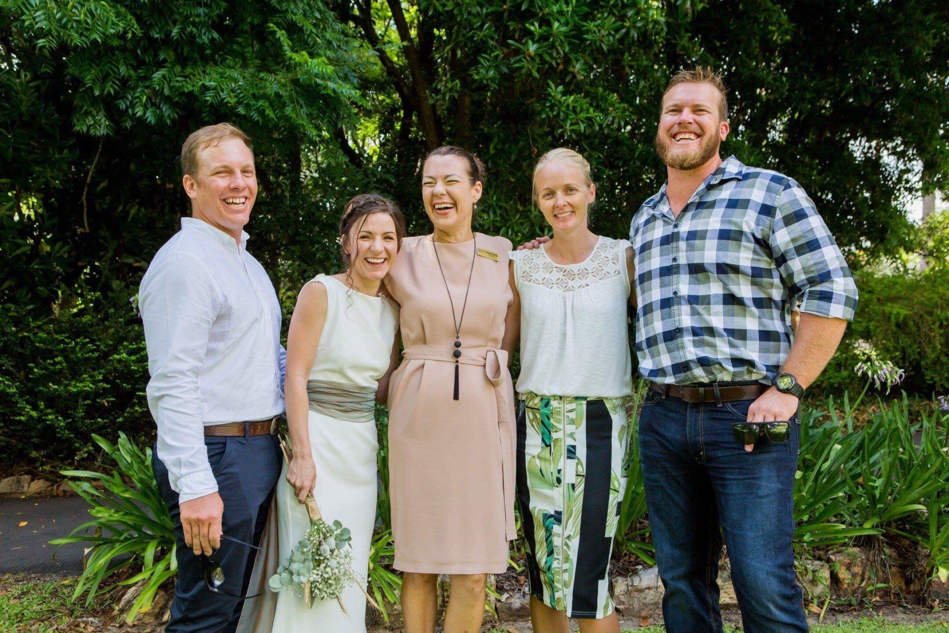 two couple newly married all laughing wit their celebrant under a tree in Noosa Botanic Gardens
