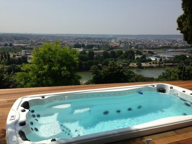 Un bain à remous est installé sur une terrasse en bois surplombant une rivière