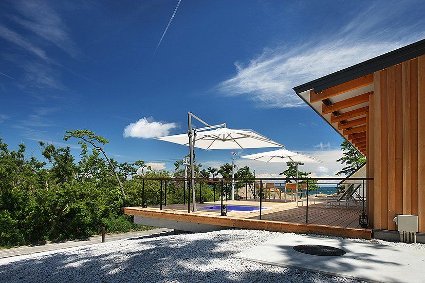 Une maison en bois avec une terrasse et des parasols dessus