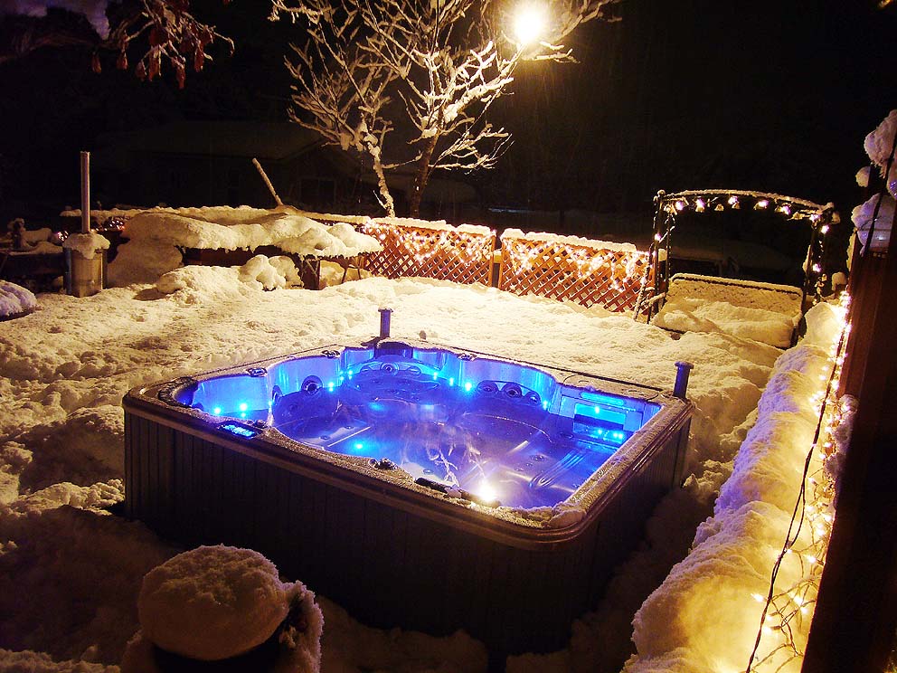 Un jacuzzi est éclairé dans la neige la nuit