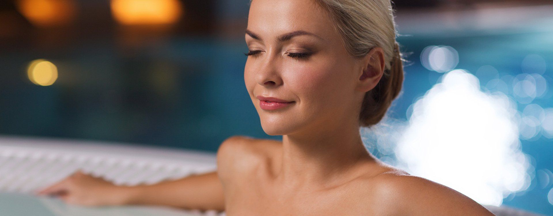 Une femme est assise dans un bain à remous, les yeux fermés.