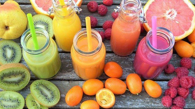 Une table garnie de smoothies, de fruits et de framboises.