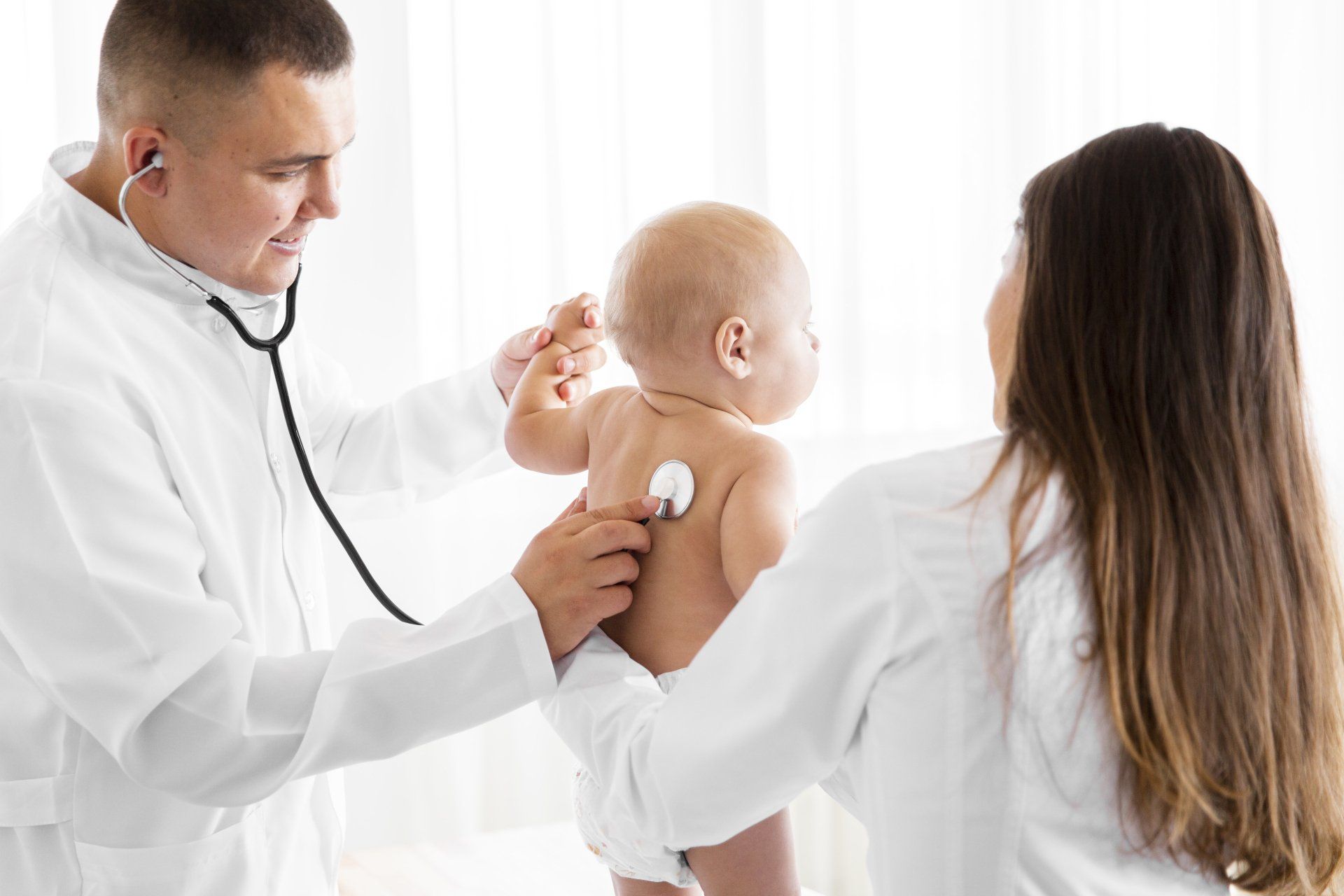 Un médico está examinando a un bebé con un estetoscopio.