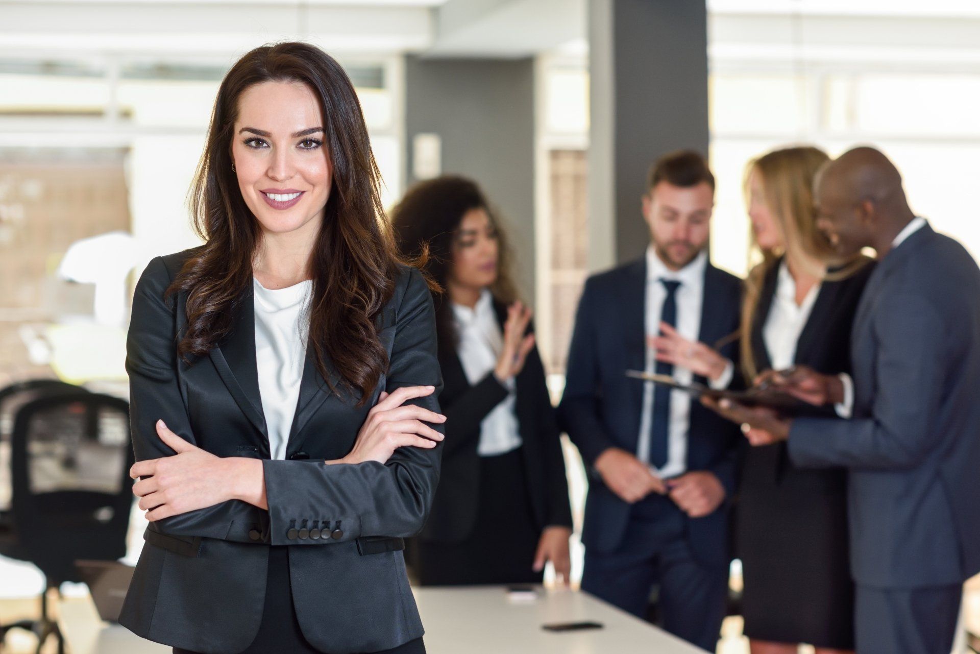 Una mujer con traje de negocios está parada frente a un grupo de gente de negocios.
