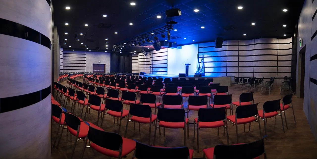 Un gran auditorio con filas de sillas y un escenario al fondo.