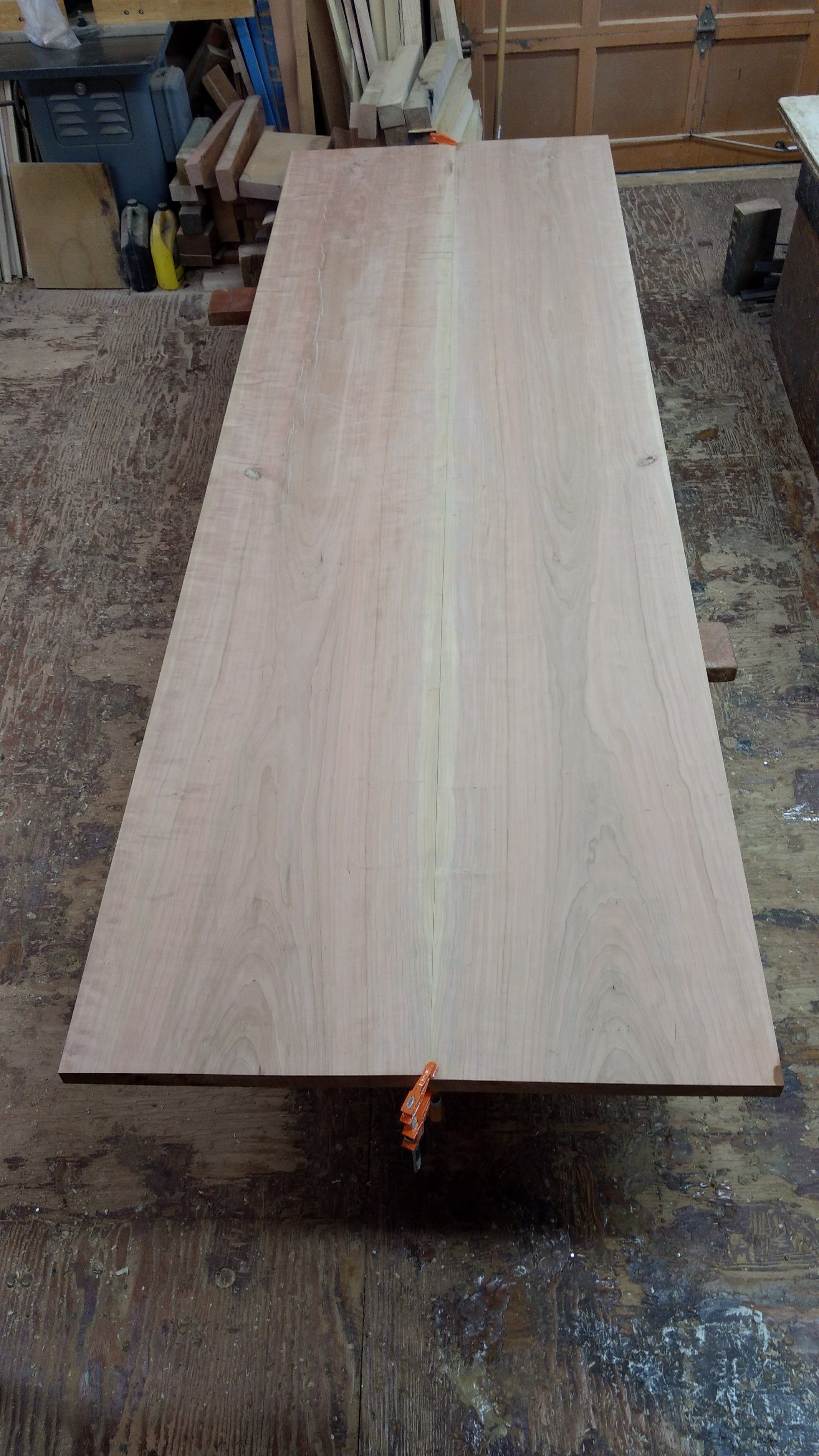 Large, rectangular wooden board lying flat on a workshop floor, likely for woodworking.