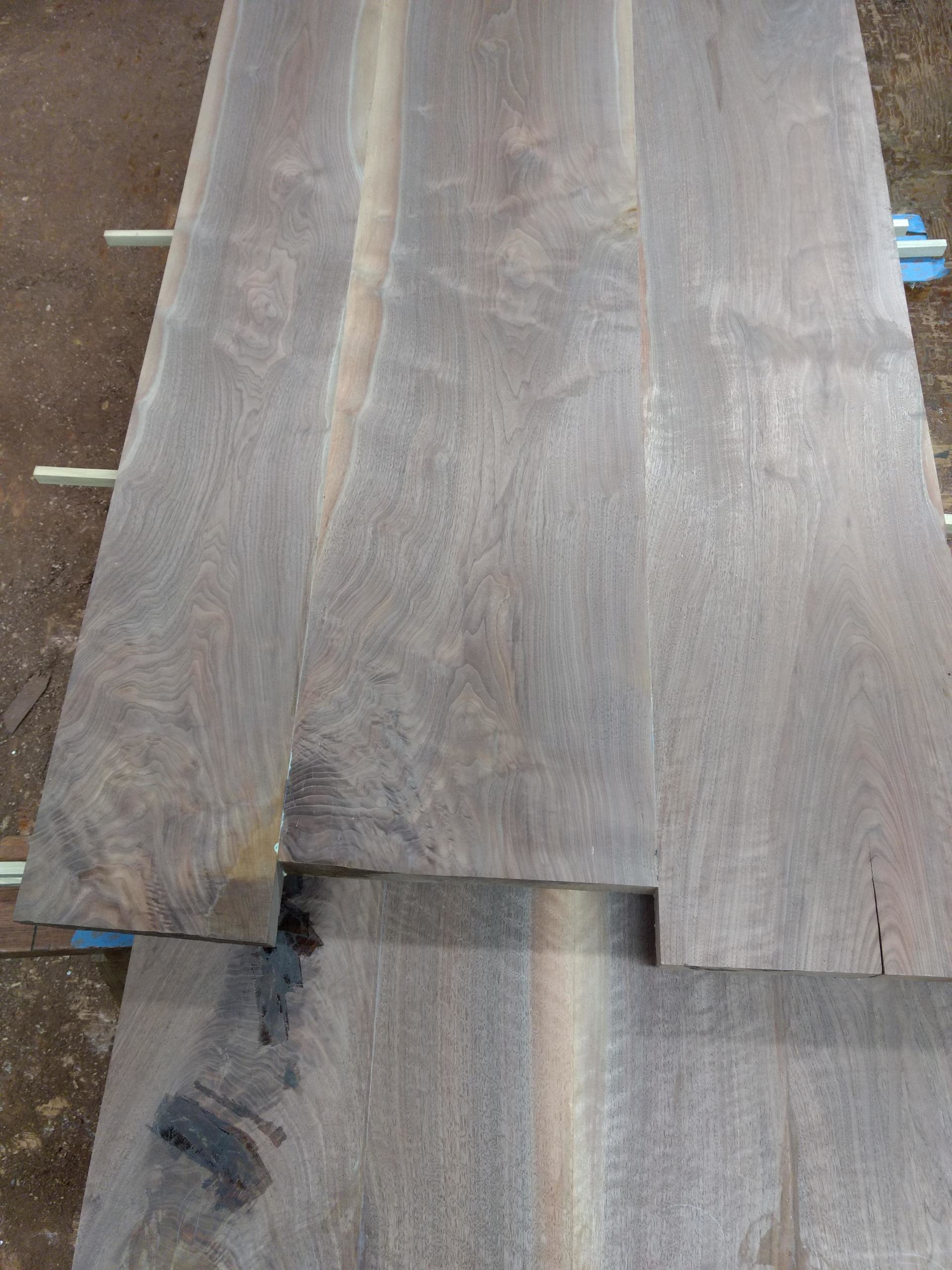 Wooden planks being glued and clamped together; workshop setting.