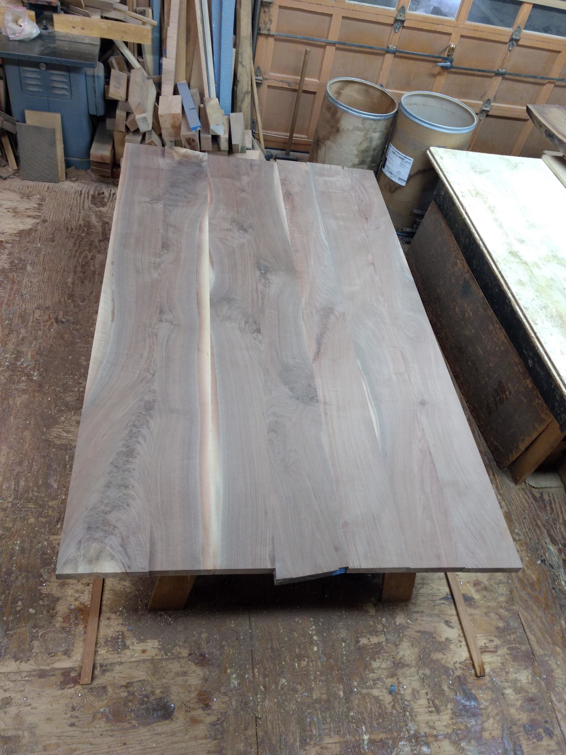 Wooden table in a workshop setting, brown wood grain, rectangular shape on a low base.