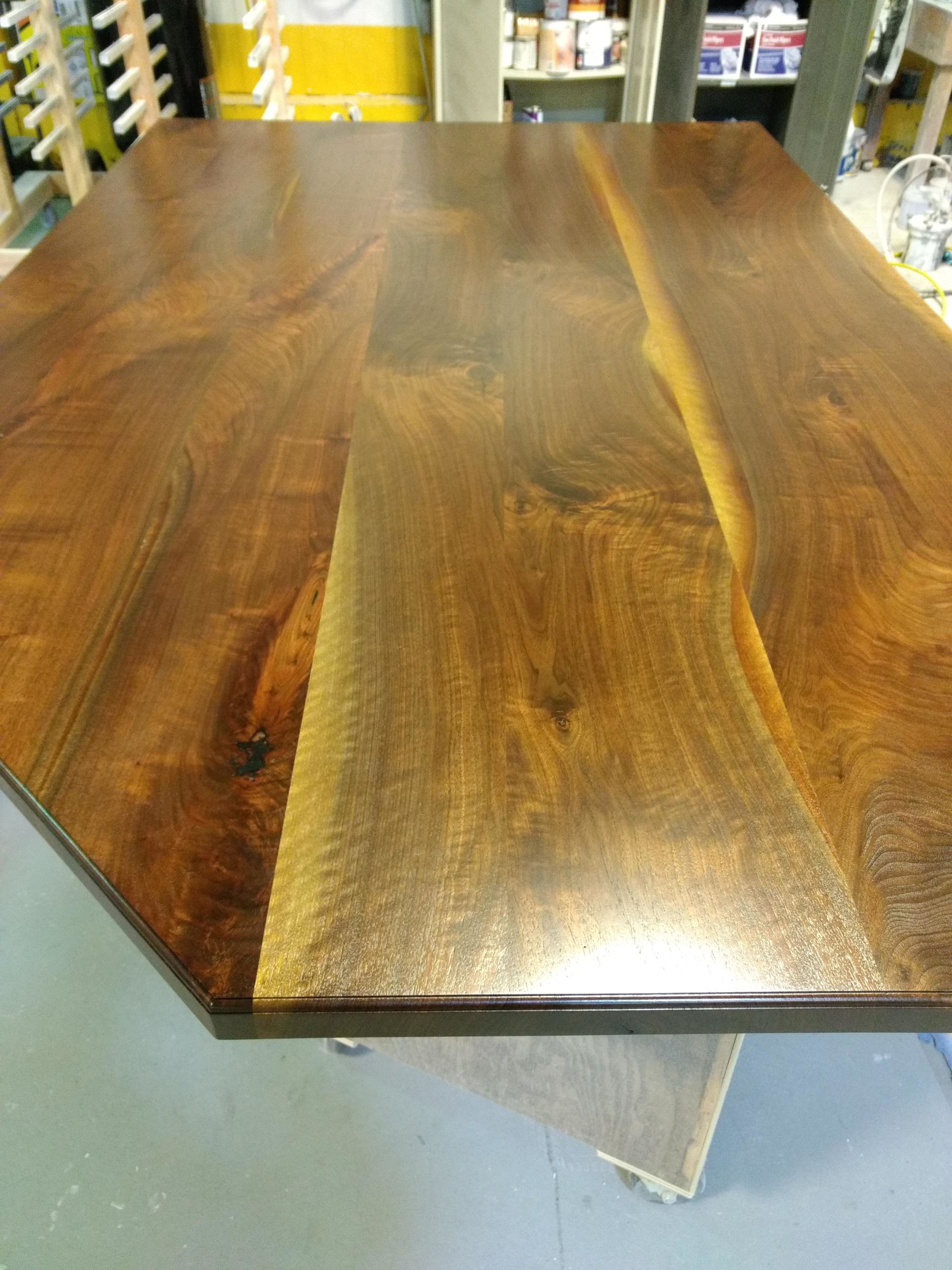 Close-up of a wooden table with a glossy finish, highlighting wood grain and color variations.