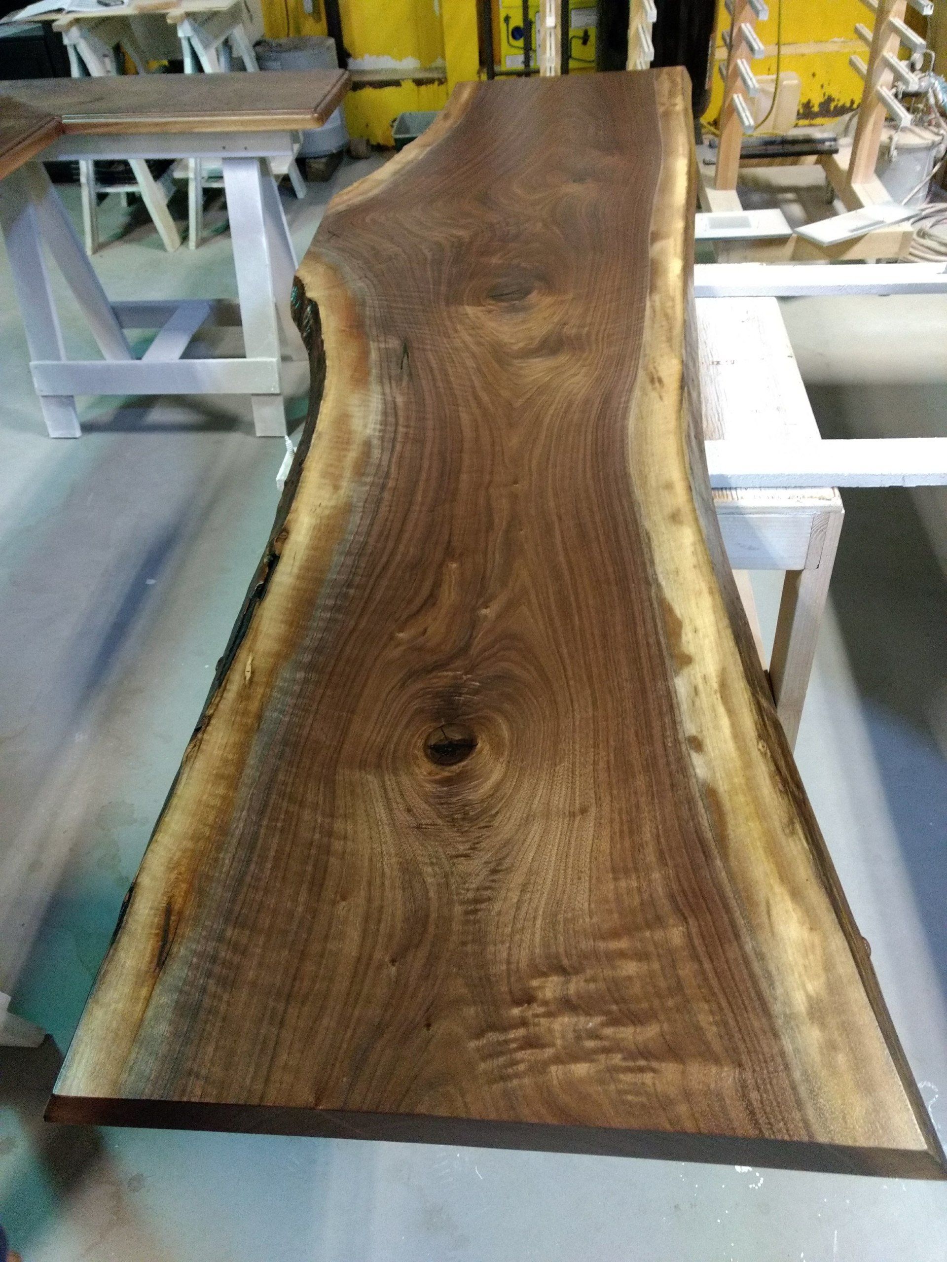 Live edge walnut wood slab on a work table, with natural grain and a knot.