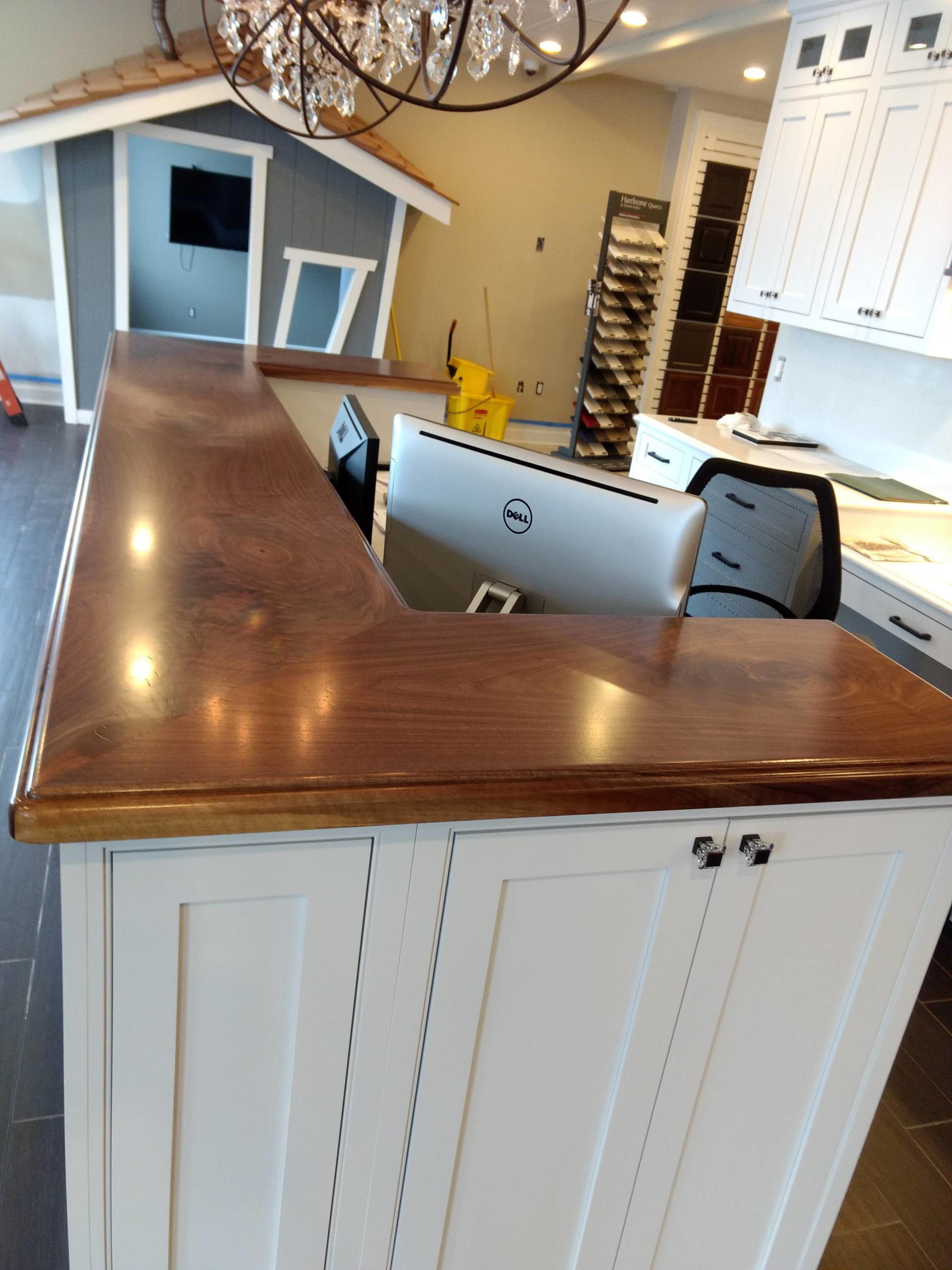 Wooden counter over white cabinets in a kitchen; small playhouse and computer visible in the background.