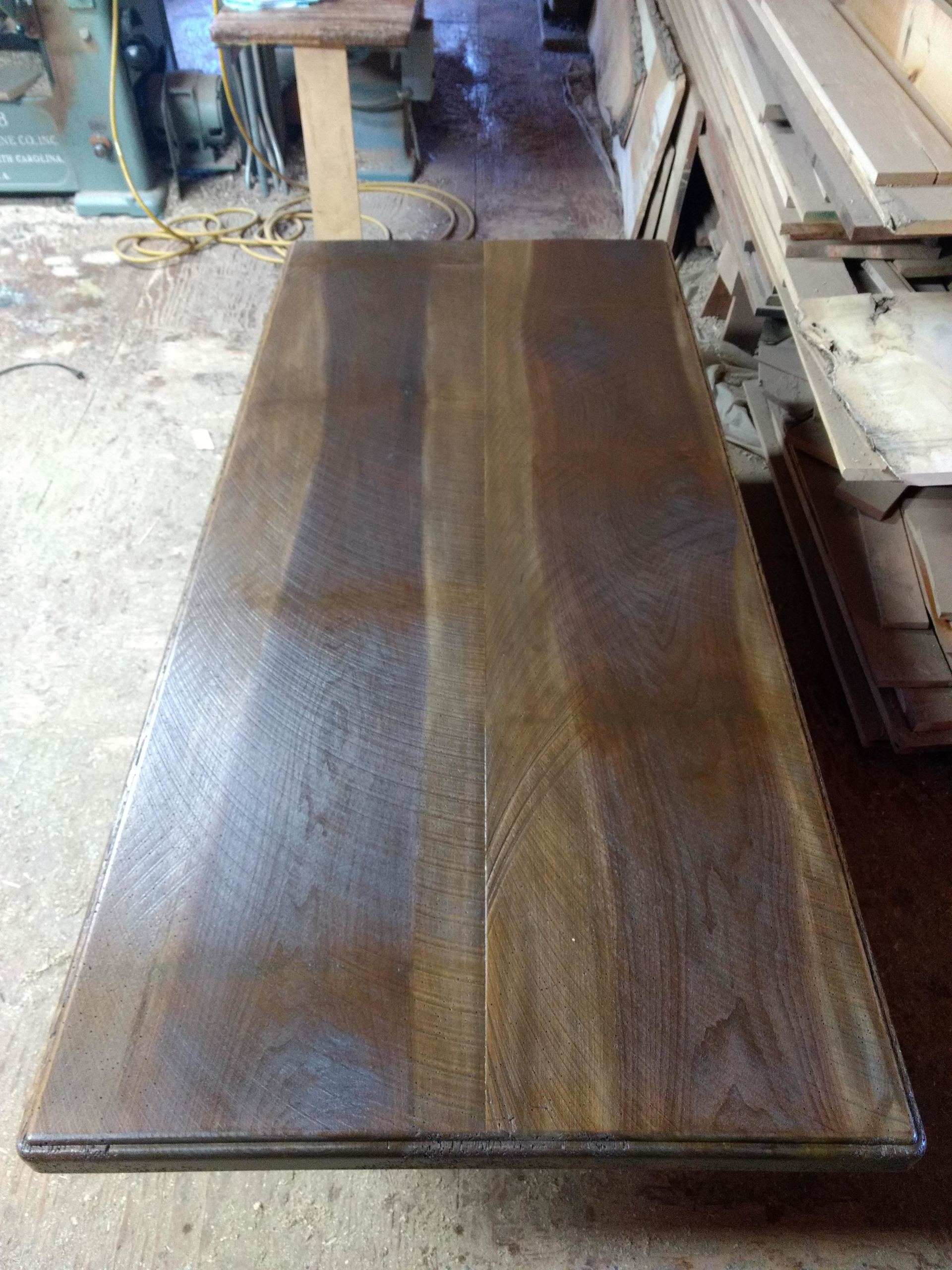 A rectangular, dark-stained wooden tabletop in a workshop setting.