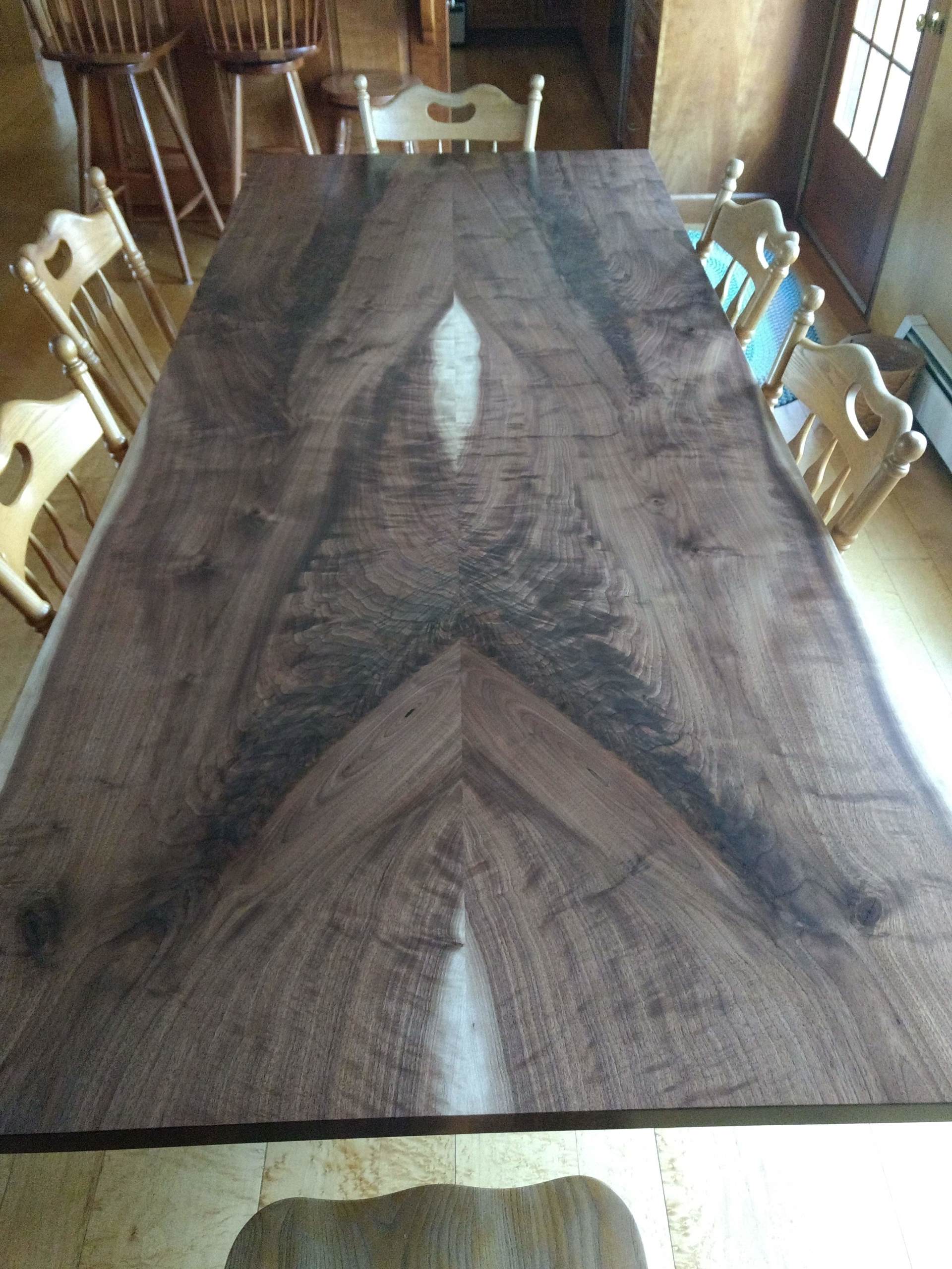 Large dark wooden table with interesting grain pattern, surrounded by wooden chairs.