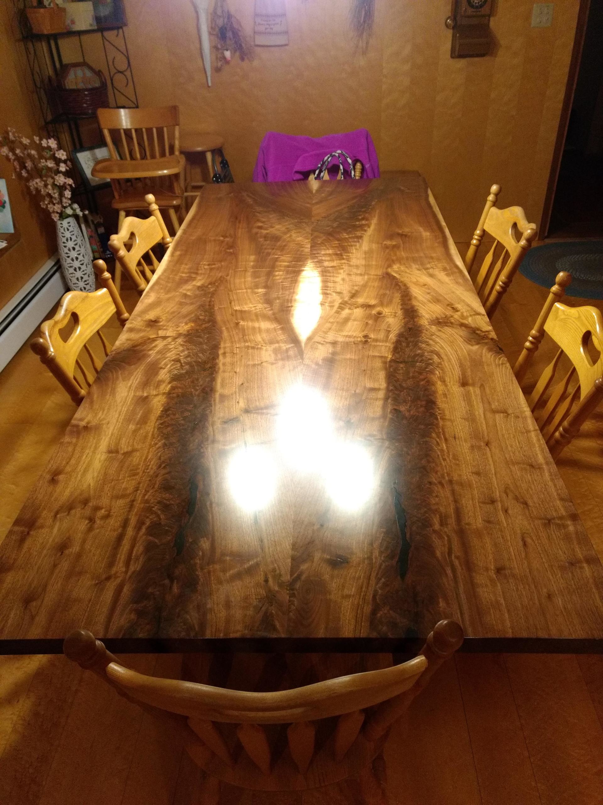 Large wooden dining table with six chairs; a vase with flowers is to the left.