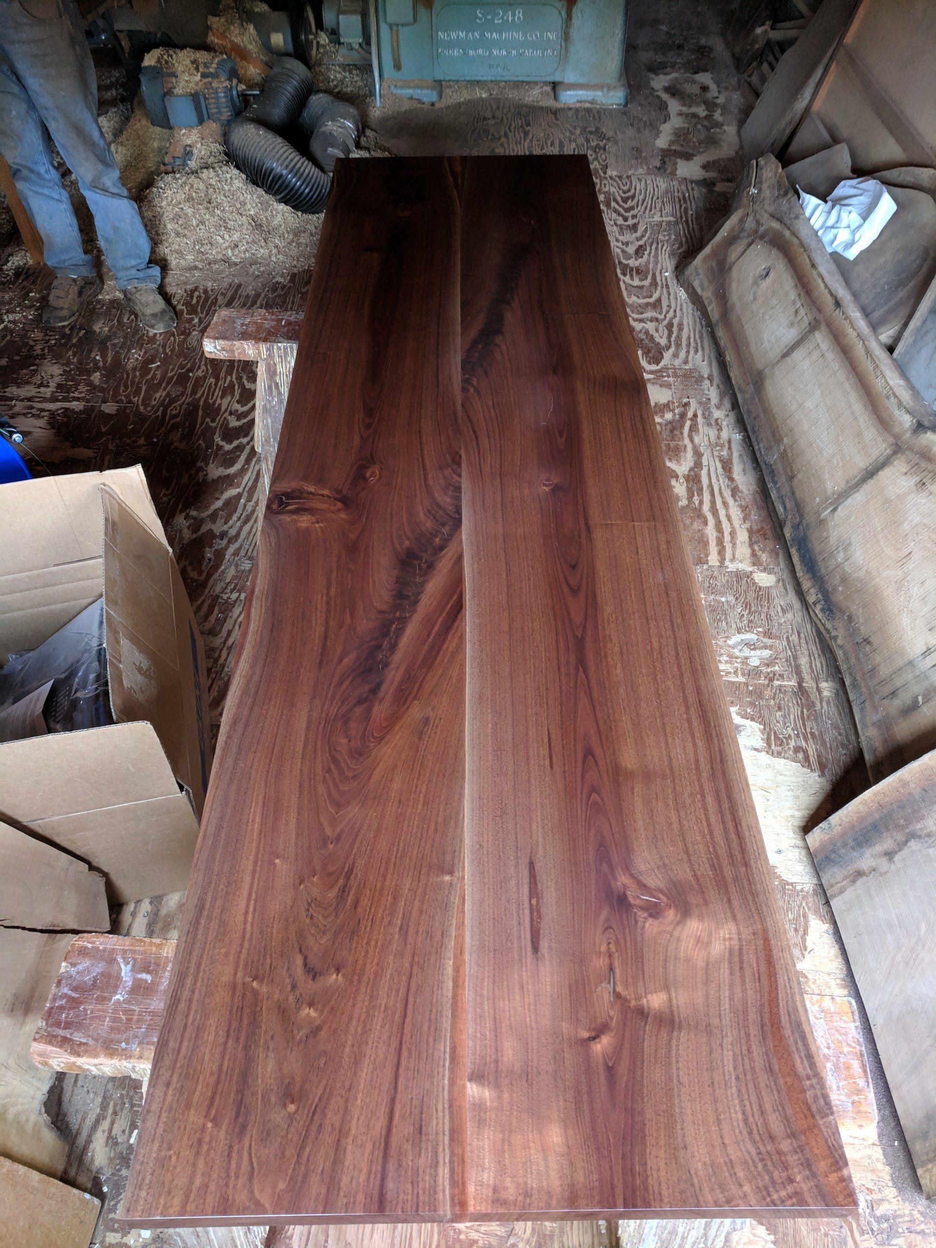 Two dark wood planks, possibly walnut, joined together, set in a wood workshop.