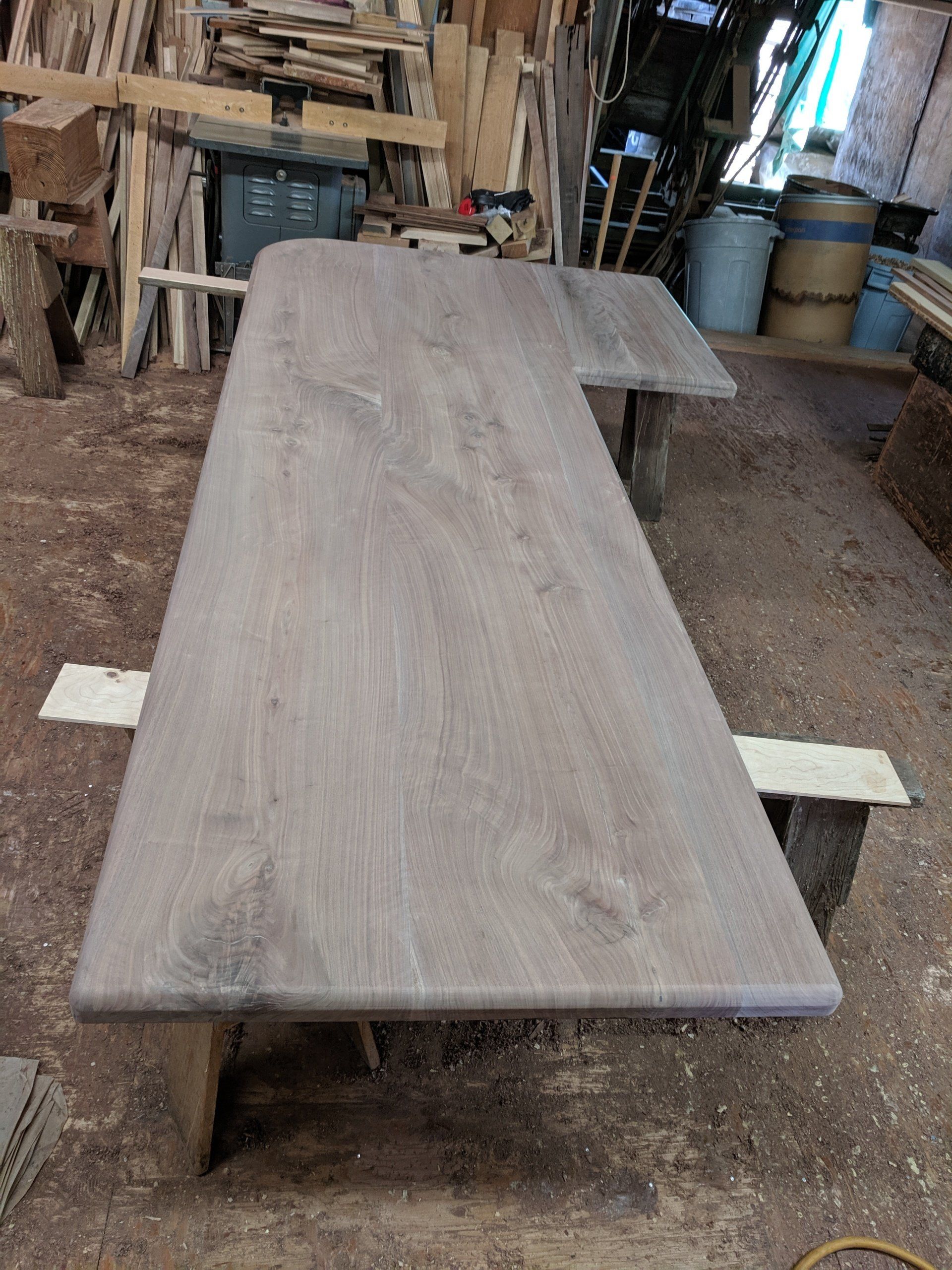 Wooden countertop with L-shaped cutout, set on sawhorses in a workshop.