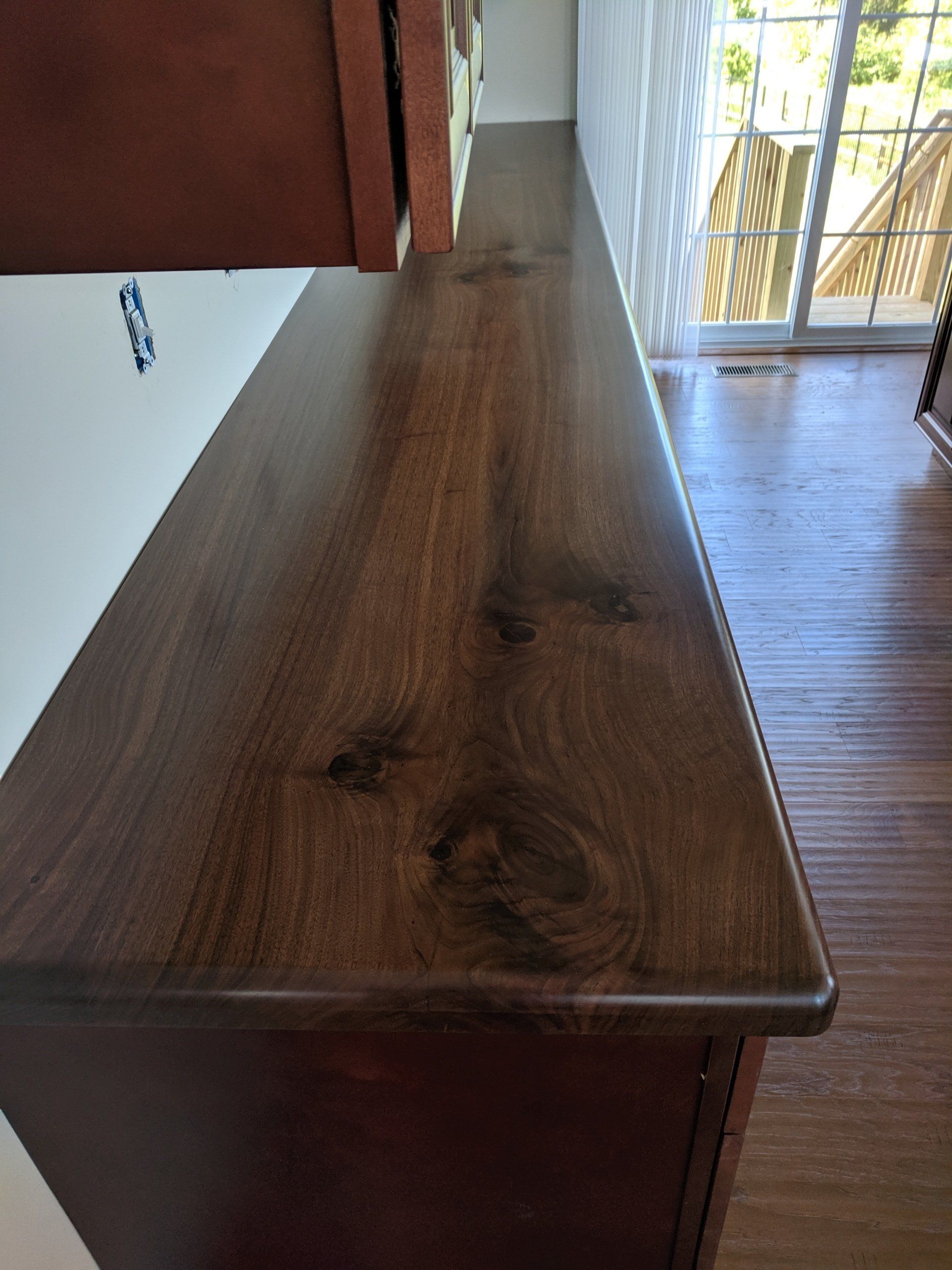 Wooden countertop with a dark stain and rounded edges.