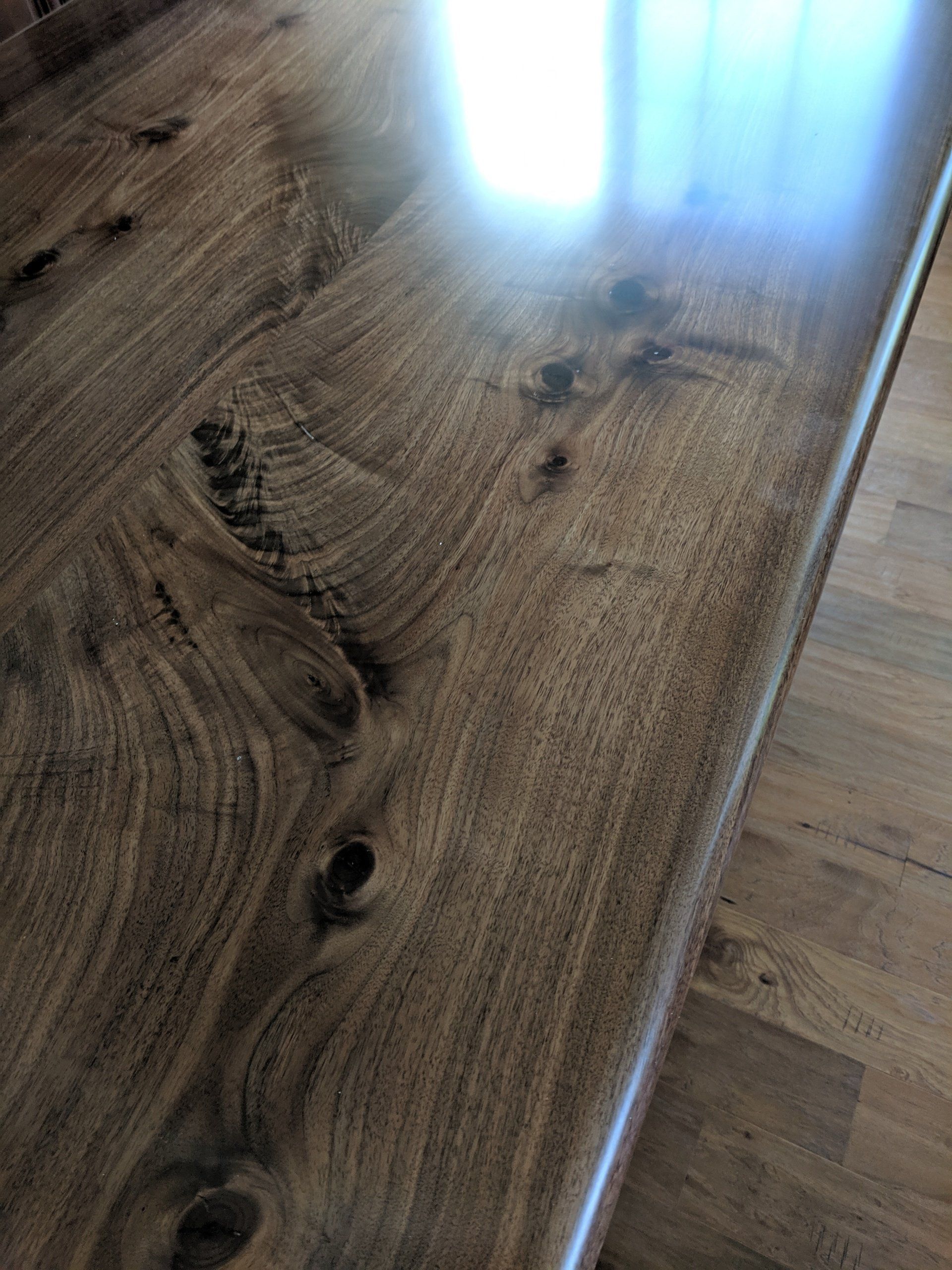 Close-up of a polished wooden surface, showing wood grain patterns and knots.