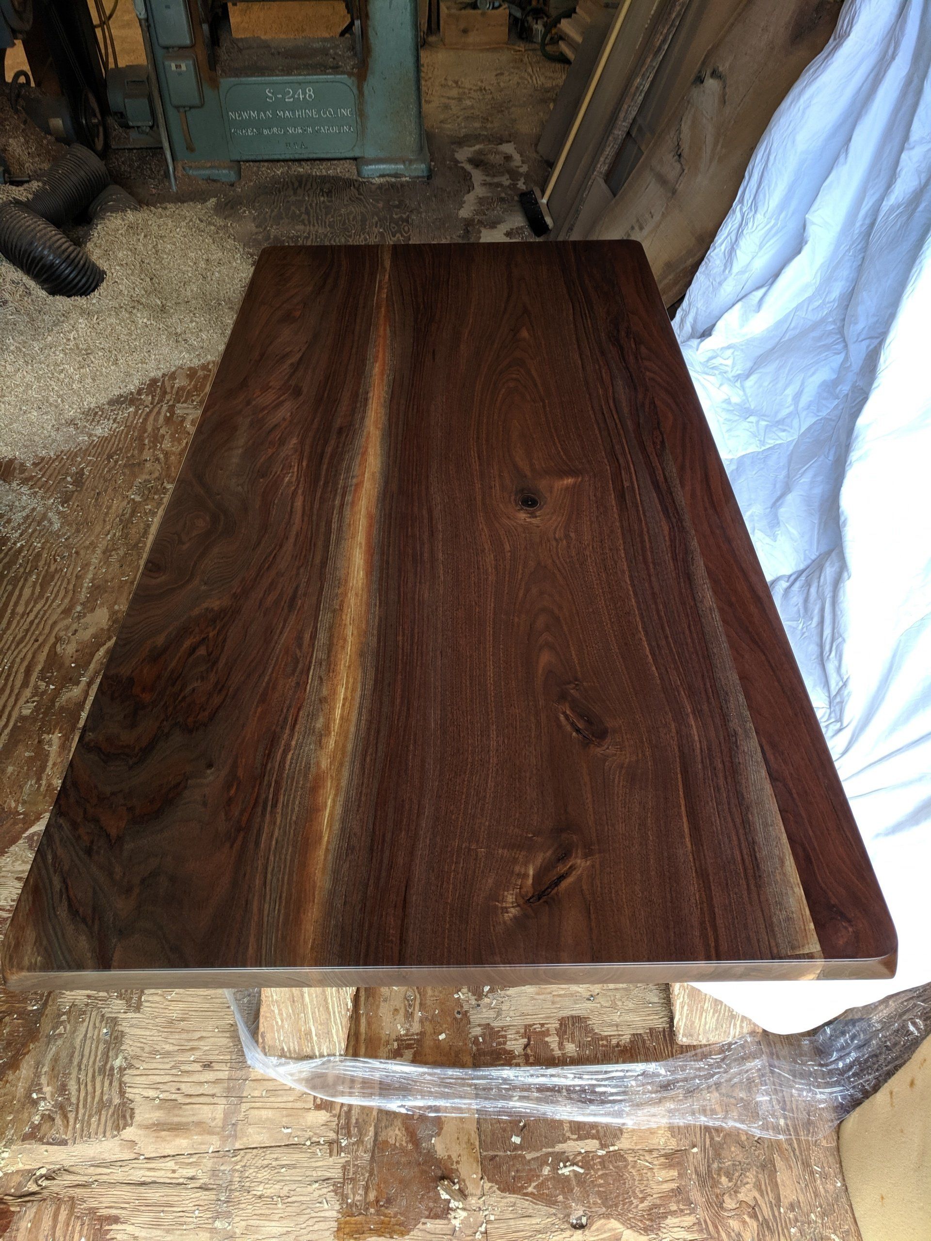 Dark wood table top with a lighter stripe down the center, on a workbench.