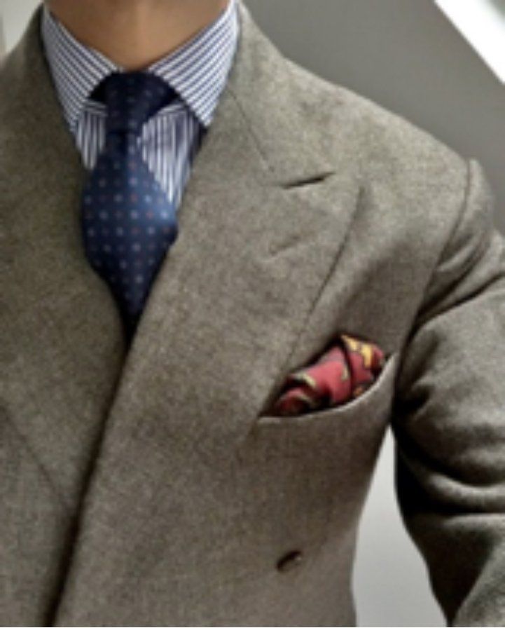 Man in a gray double-breasted suit, blue striped shirt, patterned tie, and pocket square.