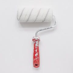 A paint roller with a red handle is sitting on a white surface.