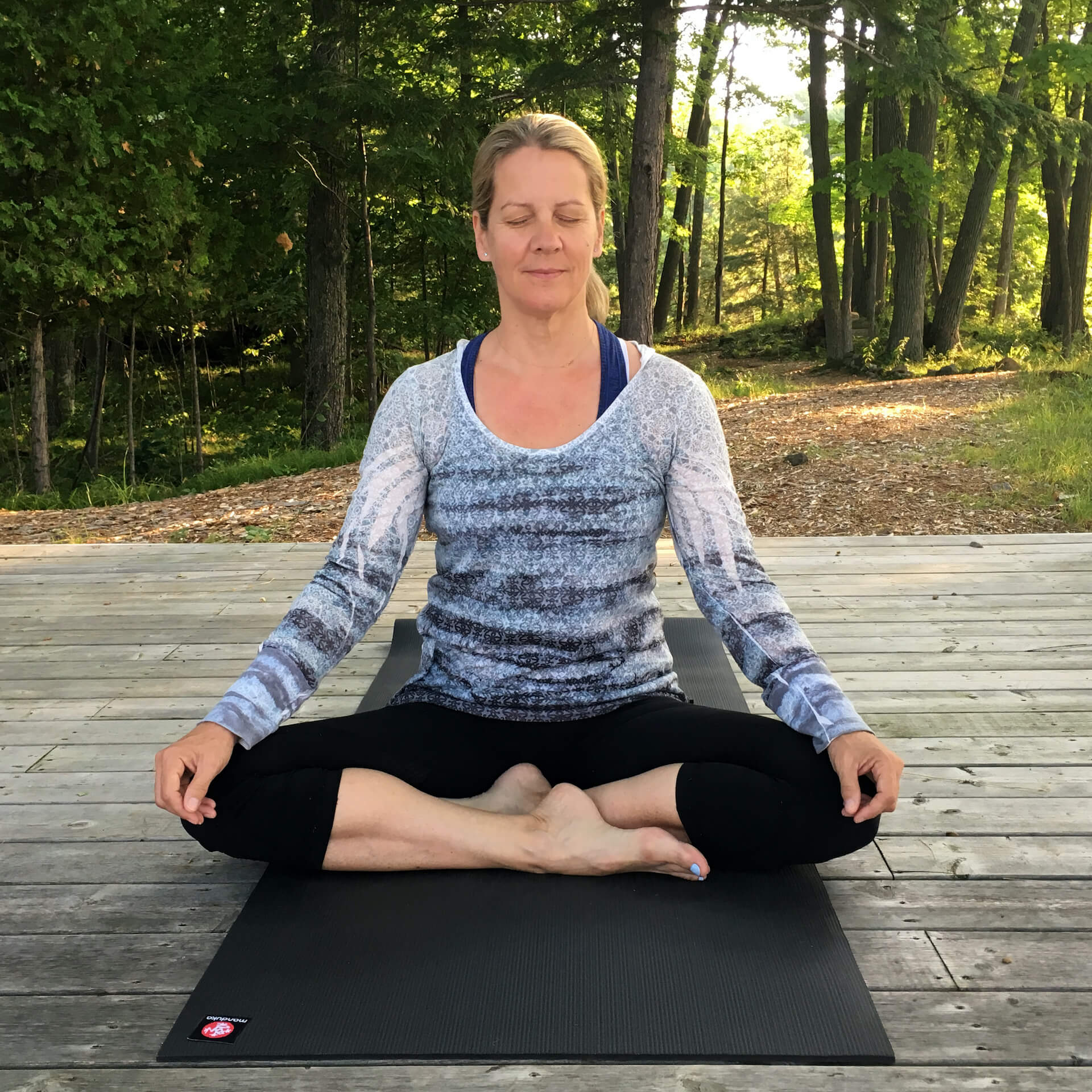 A woman is sitting in a lotus position on a yoga mat