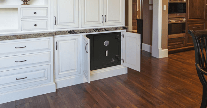 A black safe is hidden in a white kitchen cabinet, with the door open.