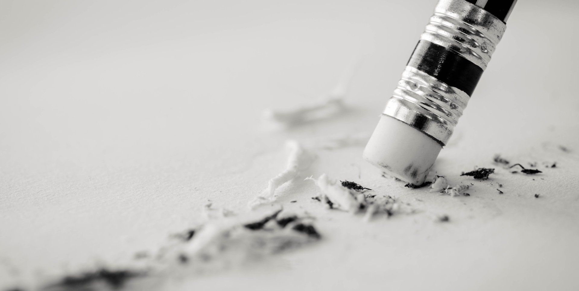 A black and white photo of a pencil erasing a piece of paper.