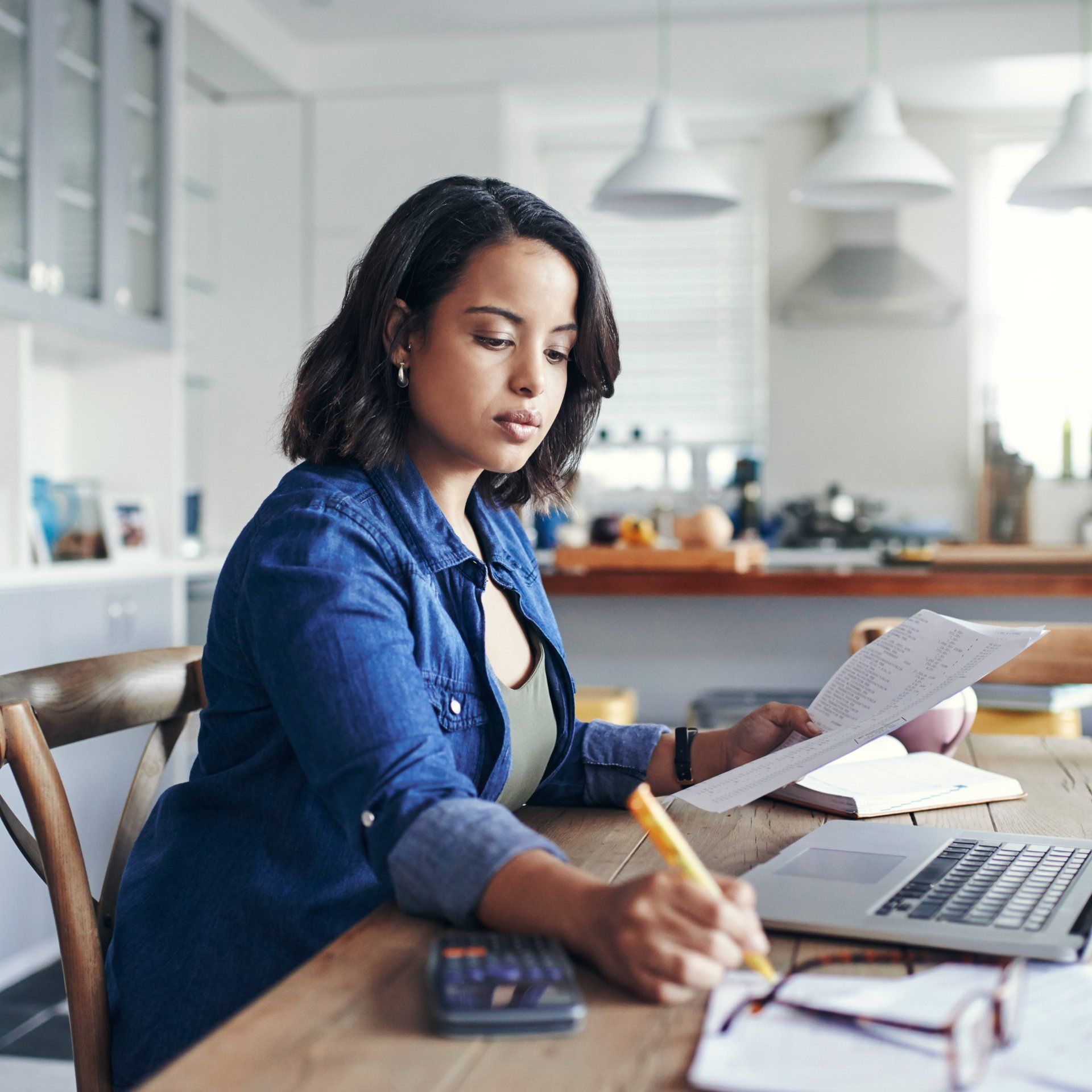 A woman is sitting at a table looking at a piece of paper.