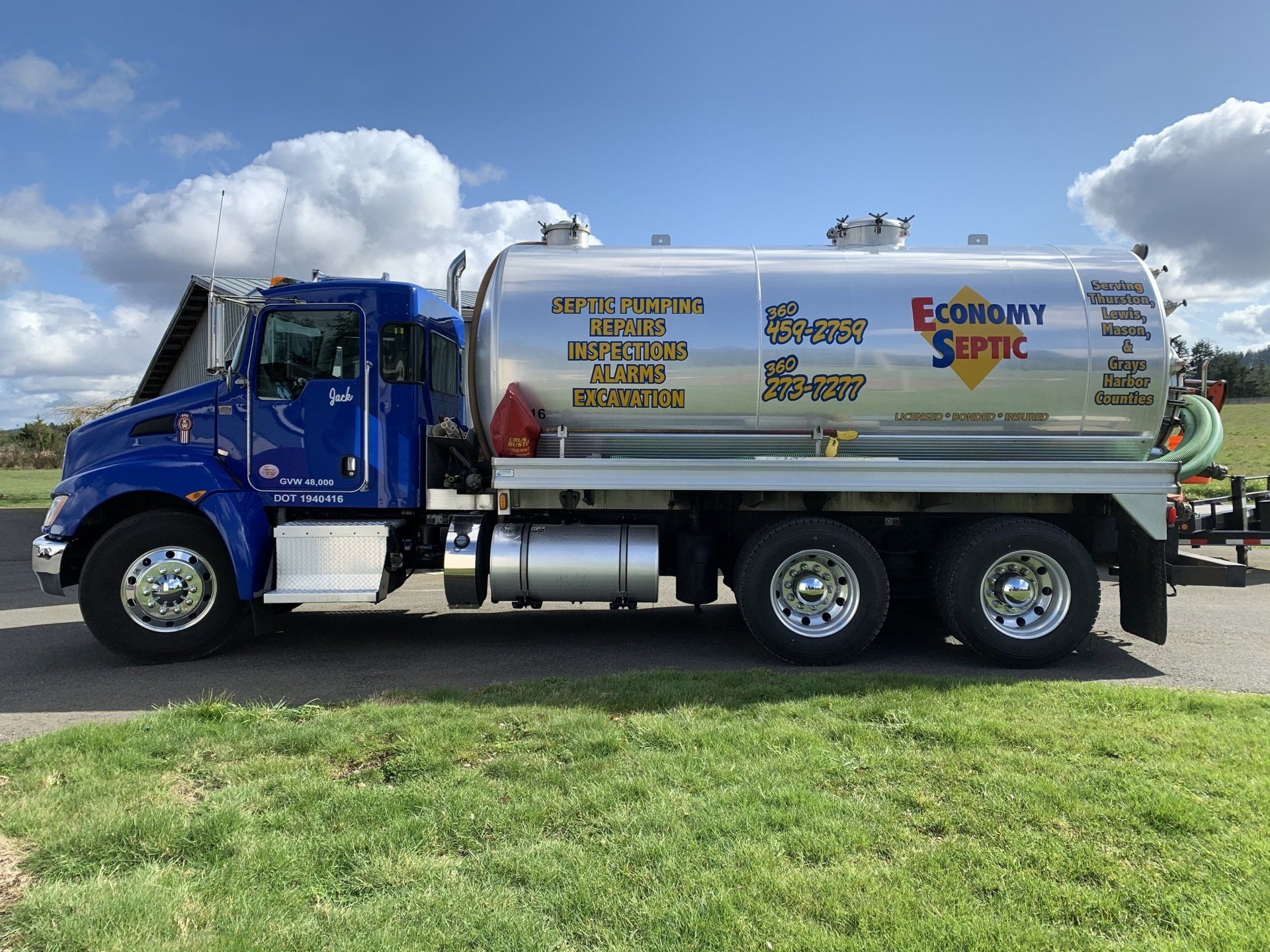 Blue septic tank truck on a green grassy hill under a blue sky, advertising