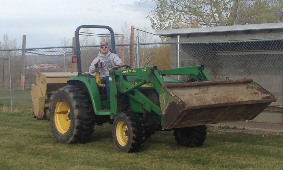 A Brother of Alpha Gamma Rho riding a tractor