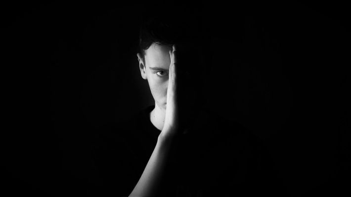 a men holding his hand in front of his face blocking the light from his right side