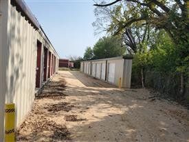 Exterior view of storage units with gravel driveway and greenery.